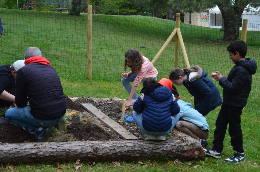 Les enfants du Centre de loisirs de La Courbe font des plantations dans leur jardin participatif. 