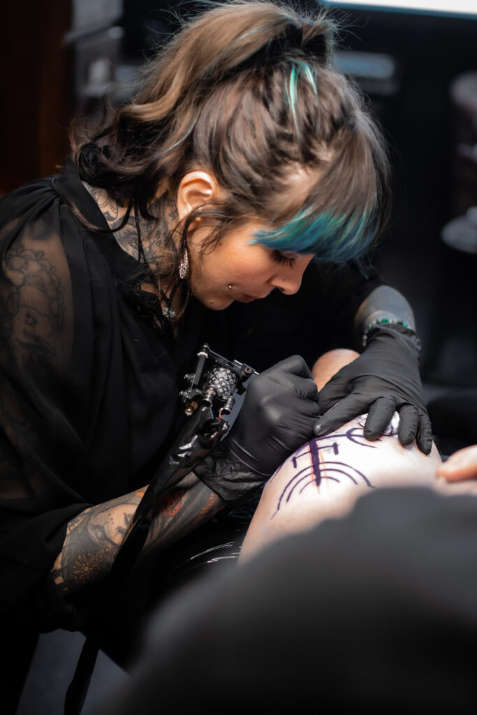 Portrait d'Ely Bournazel fondatrice de Balcksquad Tatooshop. Elle réalise un tatouage.